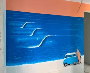 Murale con onde e furgoncino azzurro in una stanza