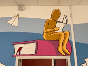 Dettaglio di una figura dorata seduta su un libro gigante