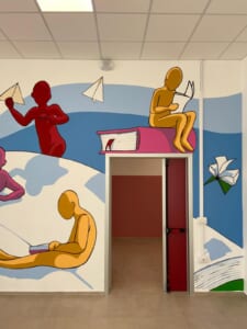 Ingresso con murale di figure che leggono