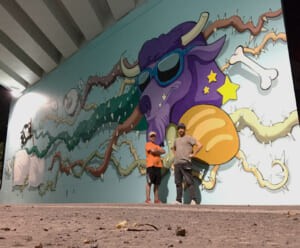 Gli artisti davanti al murale "The World of Camillas"
