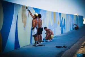 Gruppo di artisti al lavoro sul murale del molo