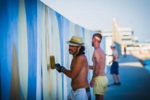 Artisti al lavoro sul murale lungo il molo