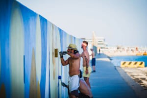 Artisti al lavoro sul murale lungo il molo