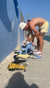 Artista al lavoro sul murale del molo