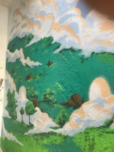 Dettaglio di un murale con prati e nuvole dipinti