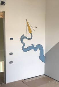 Parete dipinta con un aeroplanino di carta e una scia blu