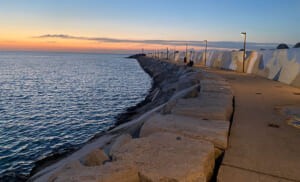 Molo del porto al tramonto con il murale sul muro frangiflutti
