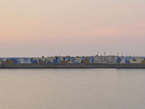 Il murale lungo il molo visto dall'acqua al tramonto
