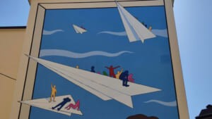 Dettaglio del murale con aeroplanini di carta nel cielo