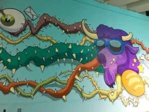 Dettaglio della mucca viola con occhiali da sole nel murale
