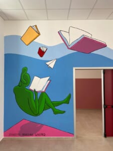 Murale con una figura verde che legge un libro