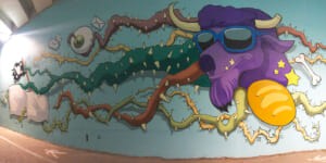Murale "The World of Camillas" con una mucca viola e una baguette